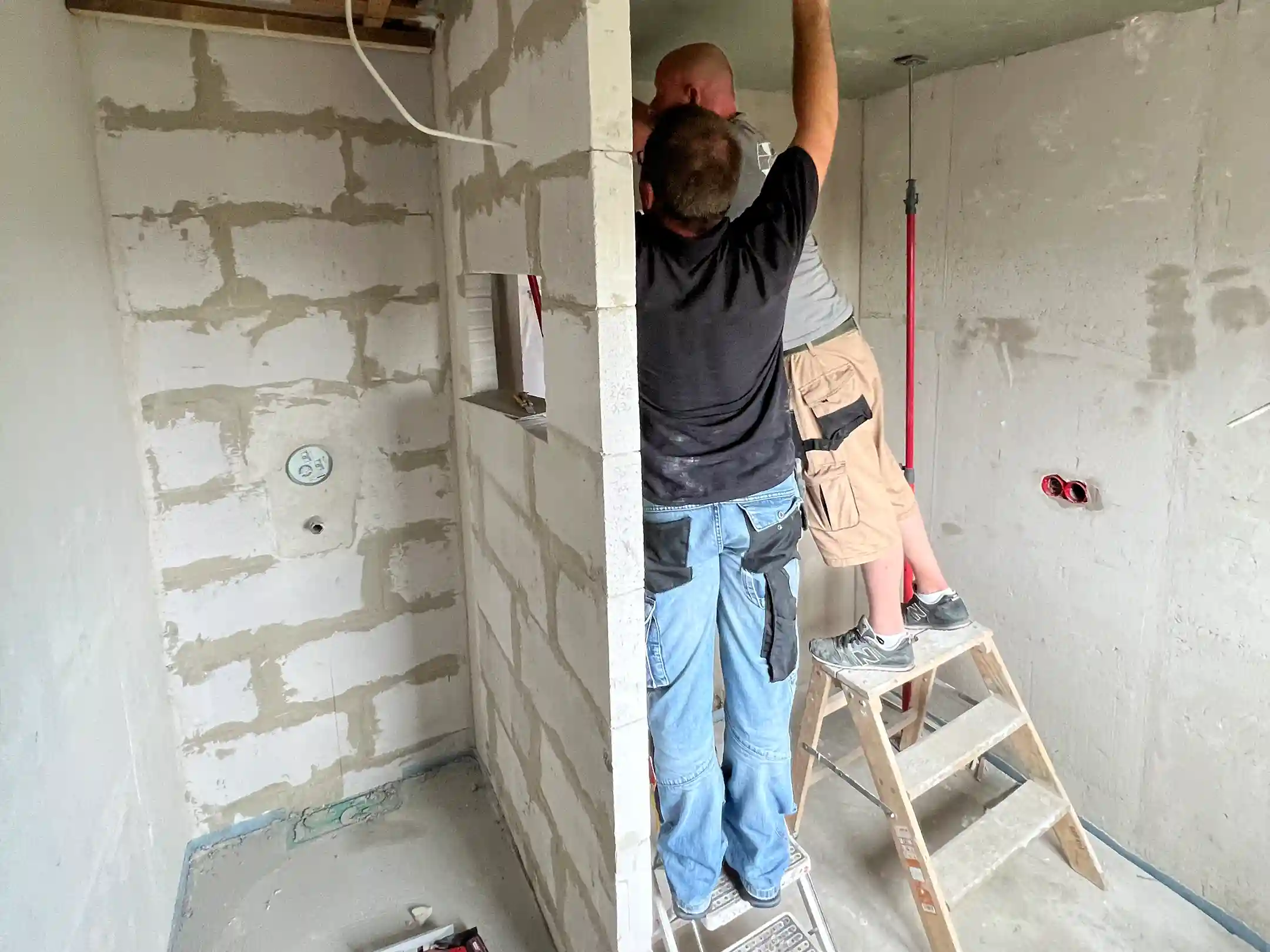 Zwei Handwerker beim Innenausbau eines Badezimmers während einer Badsanierung auf Baustelle.